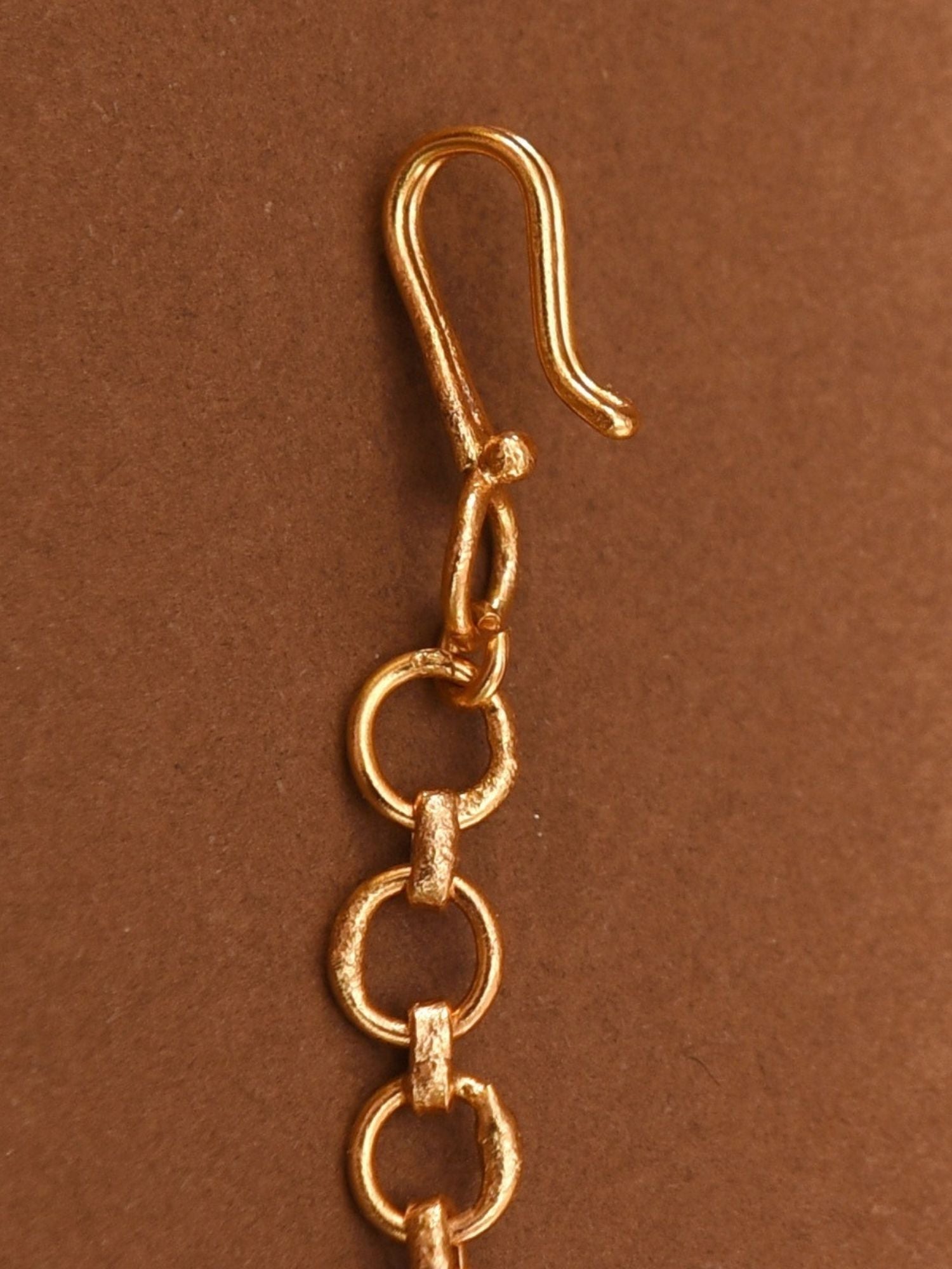 Close-up of gold plated Polki maangtikka chain links by Abdesignsjewellery on brown background