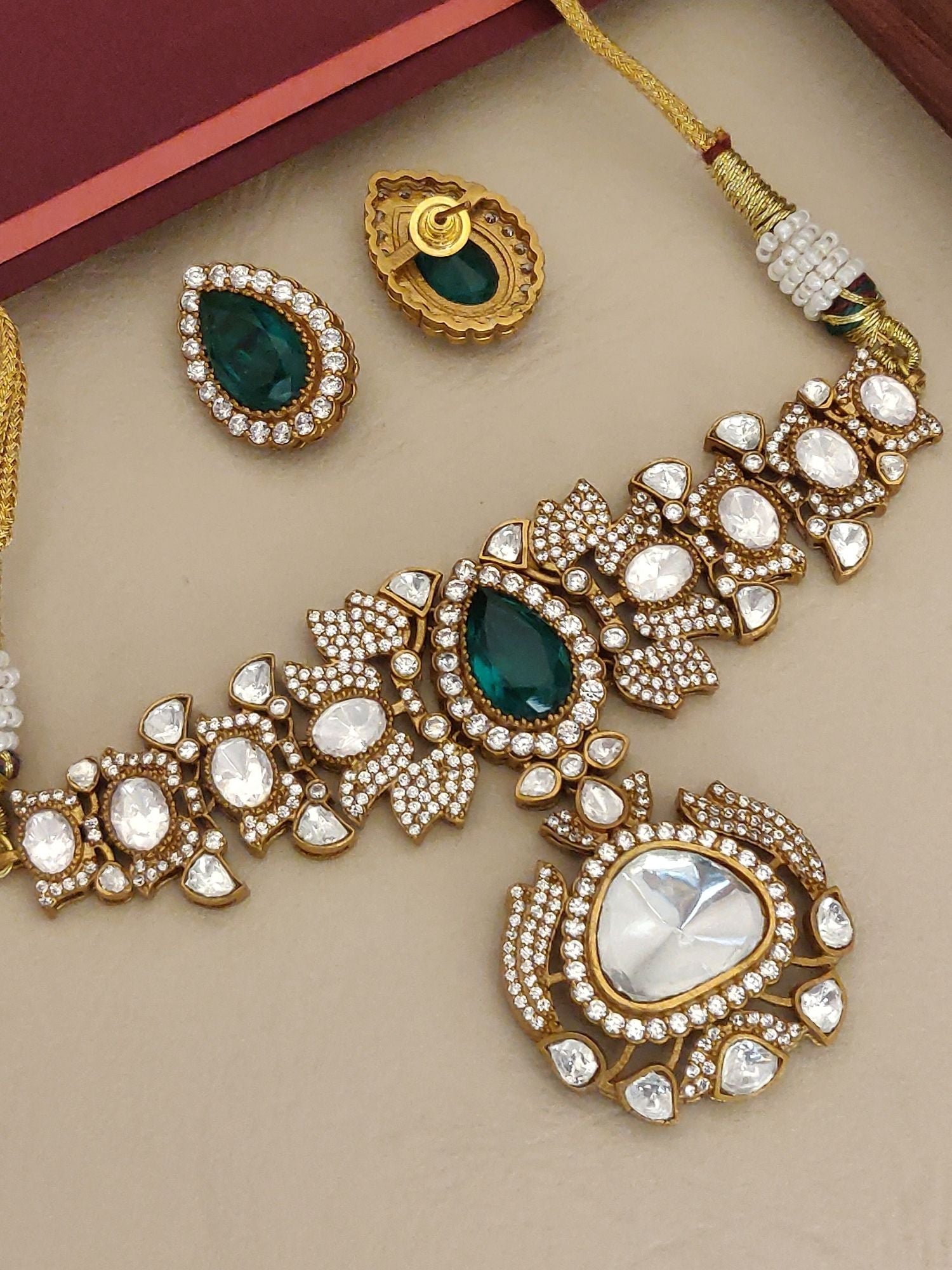 Gold plated polki necklace set with intricate design featuring green and clear gemstones