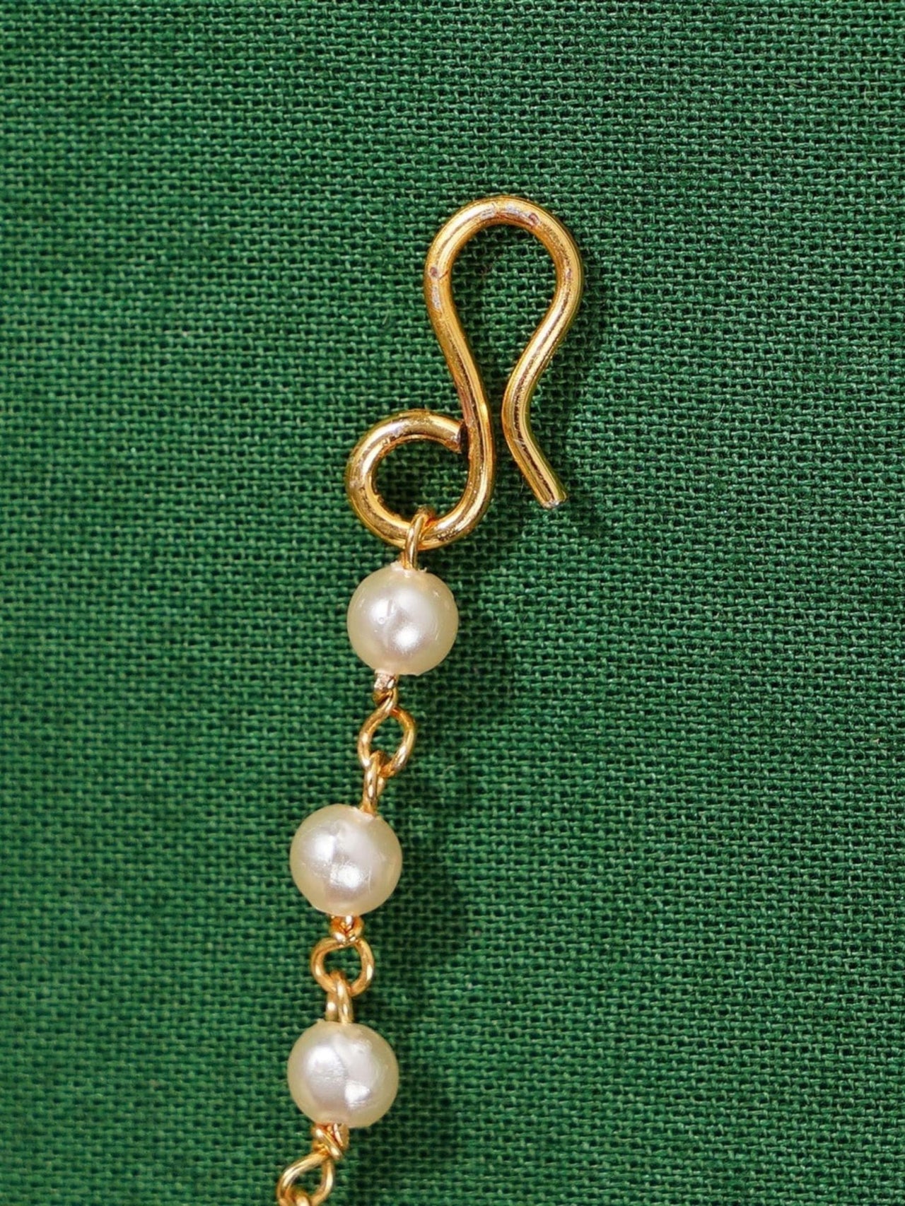 Gold Plated Polki Paachi Kundan Maangtikka with pearl beads on green fabric background