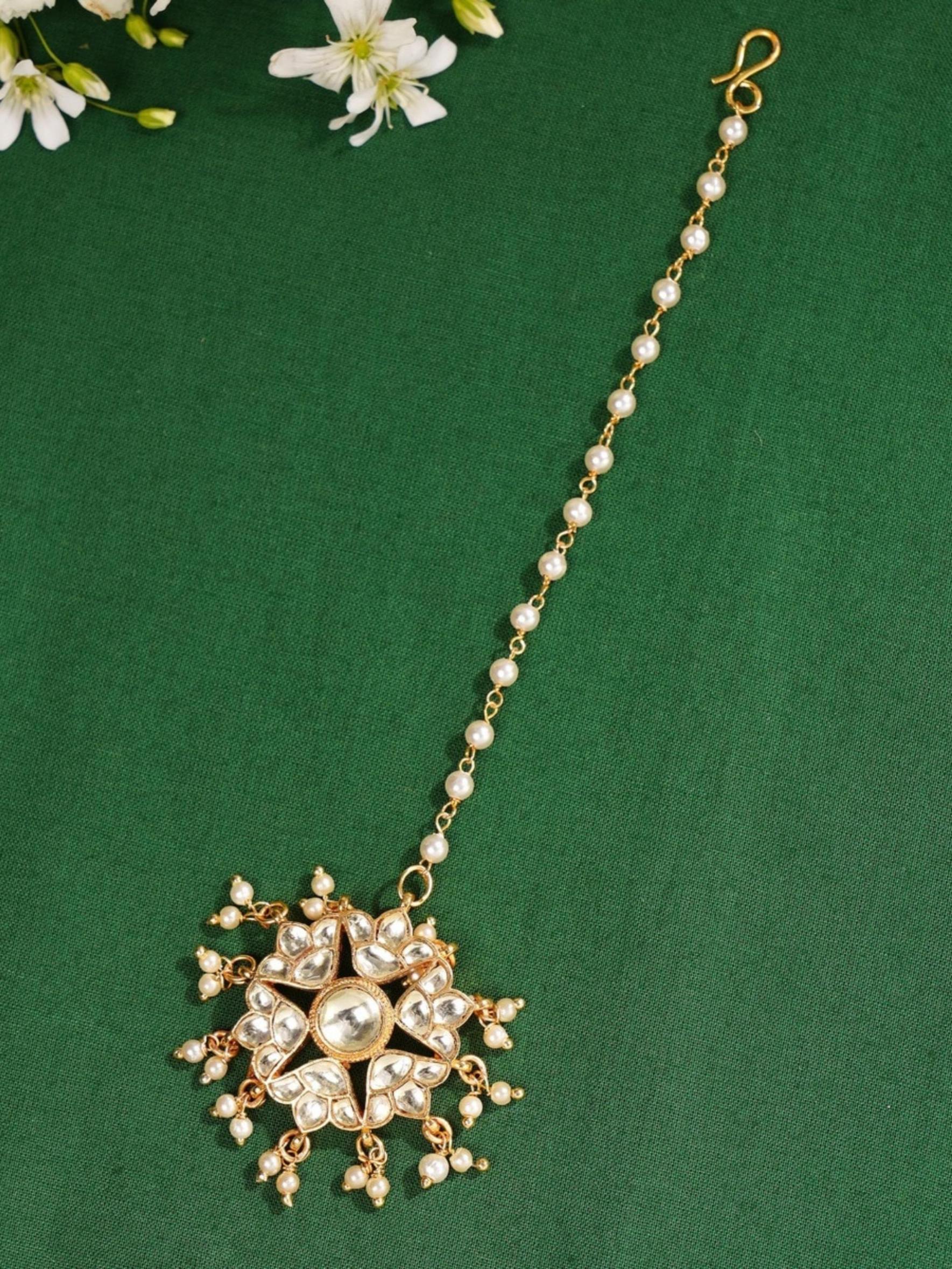 Gold Plated Polki Paachi Kundan Maangtikka with intricate pearl and stone detailing on green background