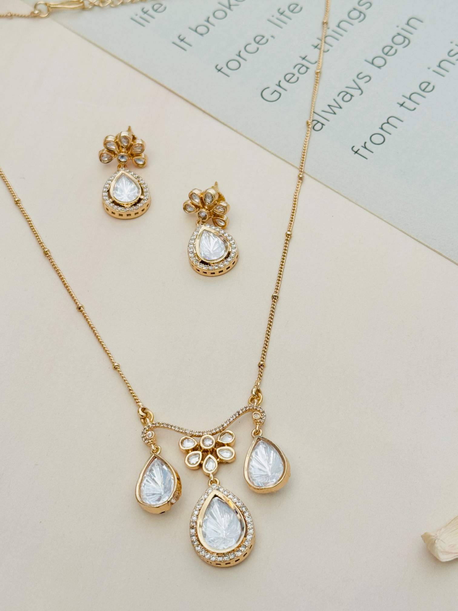 Gold Plated Polki Pendant Chain Set with matching earrings by Abdesignsjewellery on a beige background