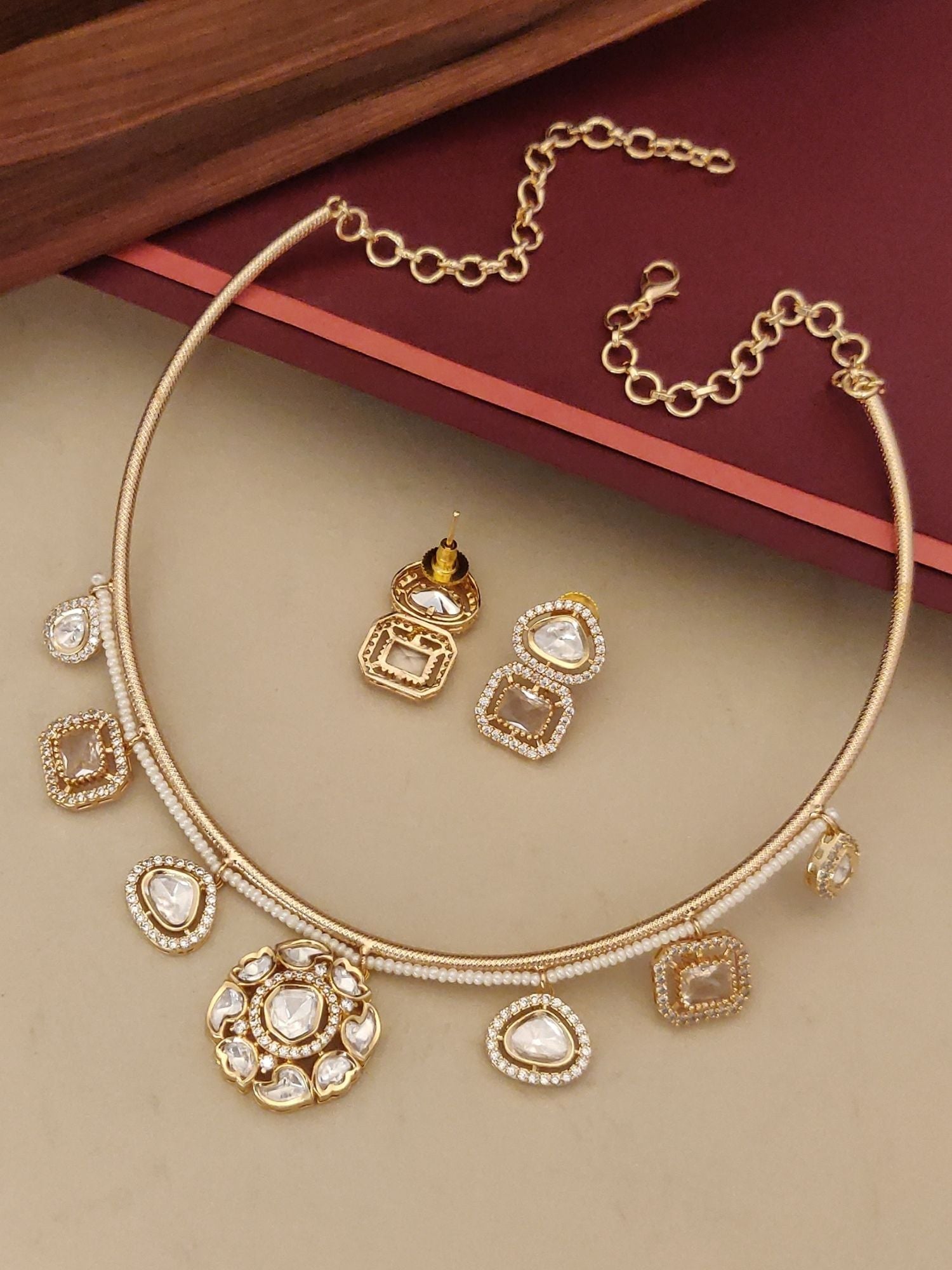 Gold Plated Polki Studed Hasli Necklace Set with matching earrings on a decorative background