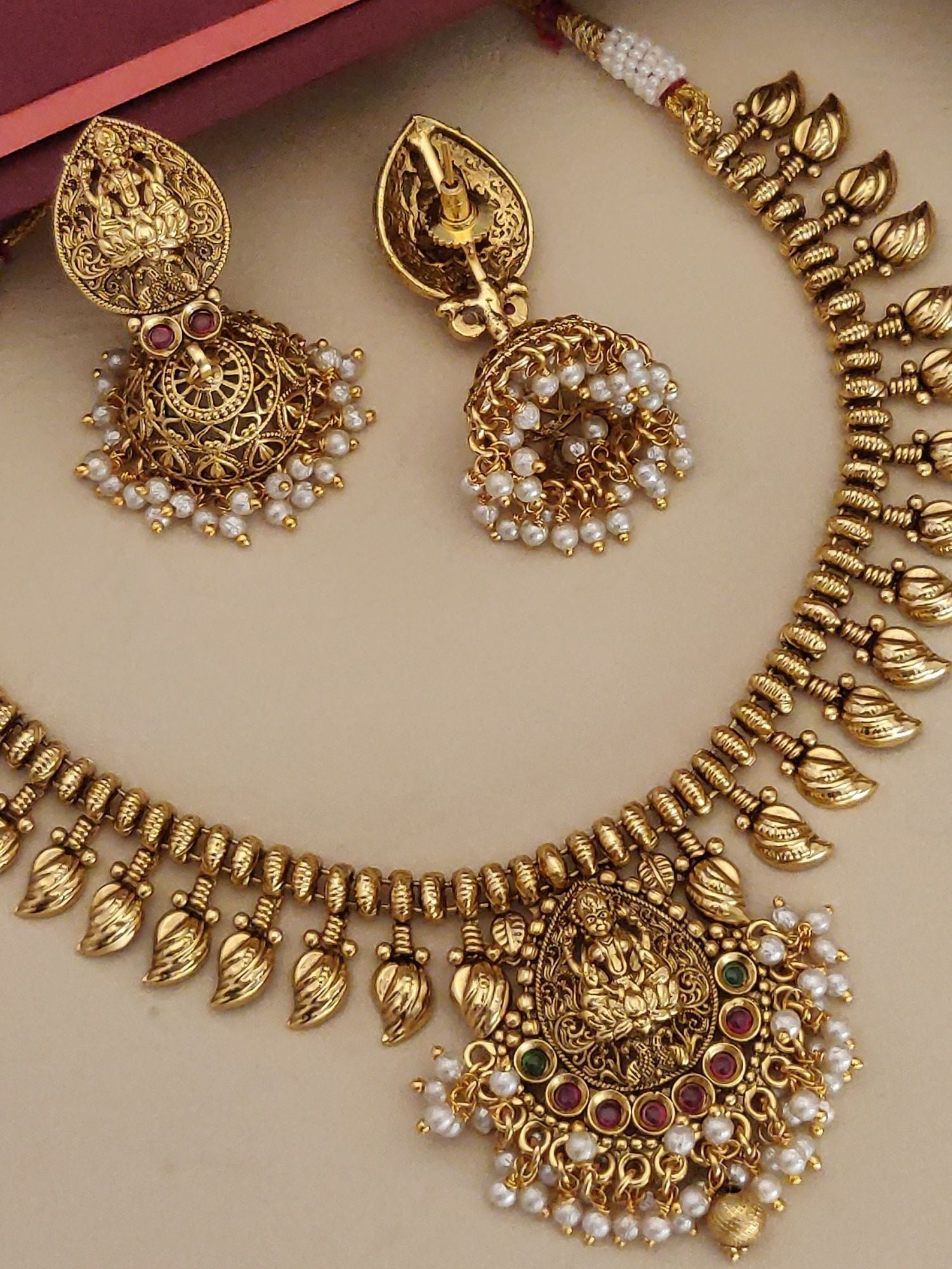 Gold plated temple necklace set with intricate design and matching earrings adorned with pearls