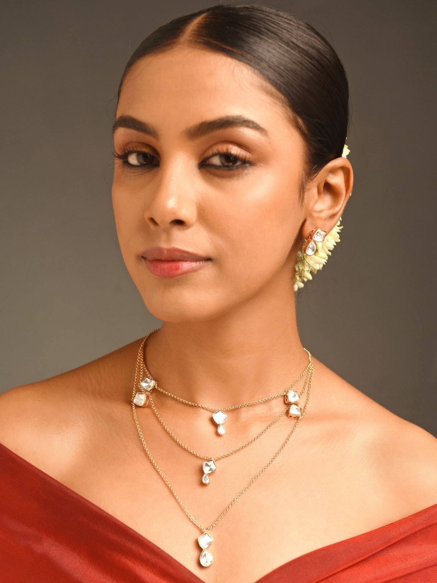 Woman wearing Gold Plated Uncut Polki Pendant Chain layered with multiple delicate chains and white stone pendants