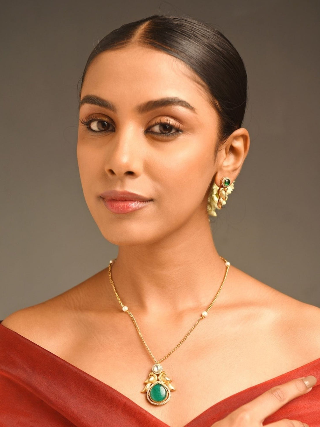 Luxurious Gold Plated Polki Pendant Chain with green stone worn by woman in red dress