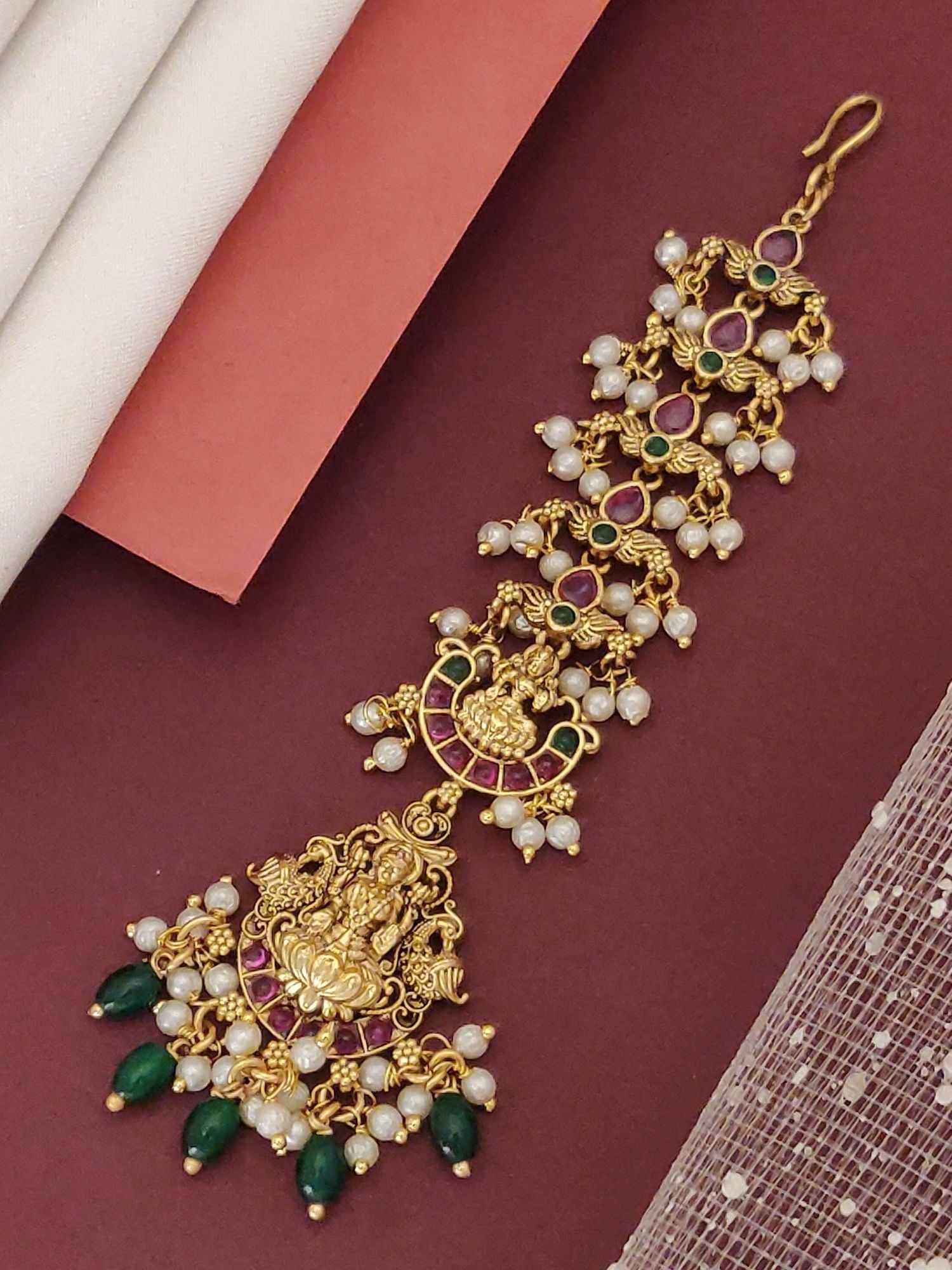 Matt gold plated head maangtikka with pearl drops green bead accents and intricate deity pendant by Abdesignsjewellery