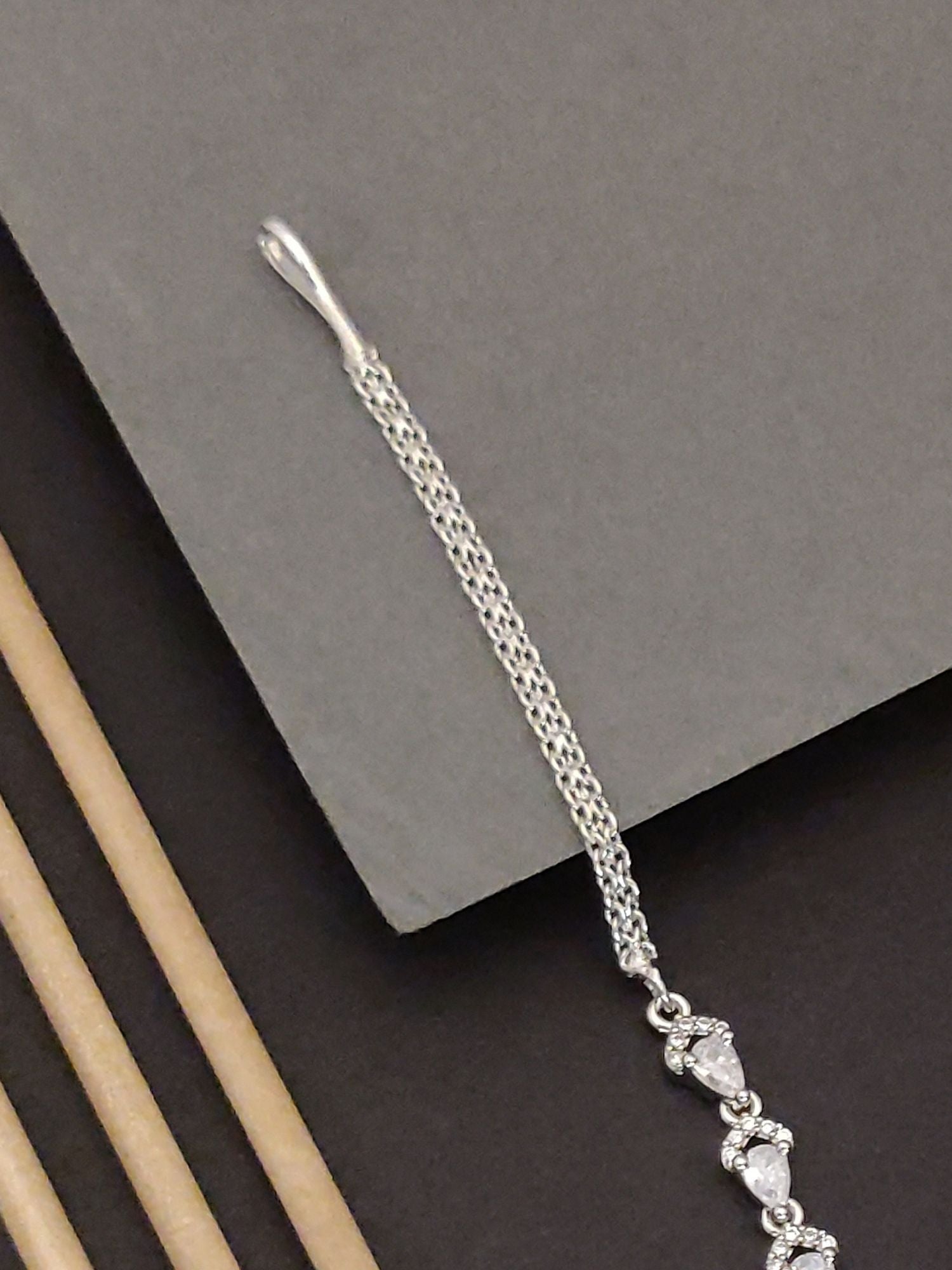 Silver Plated American Diamond Drop MaangTikka with elegant design on a textured backdrop