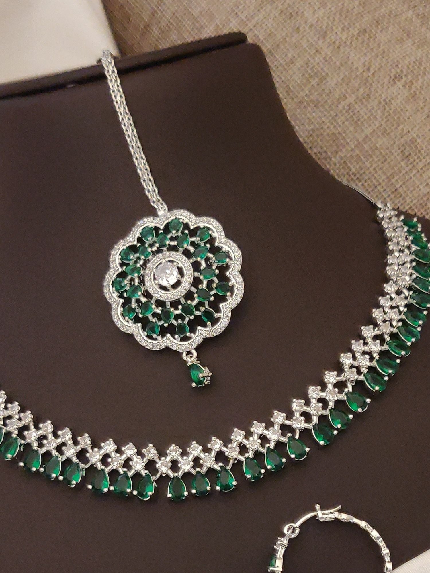 Silver plated American diamond necklace set featuring green gemstones and intricate design.