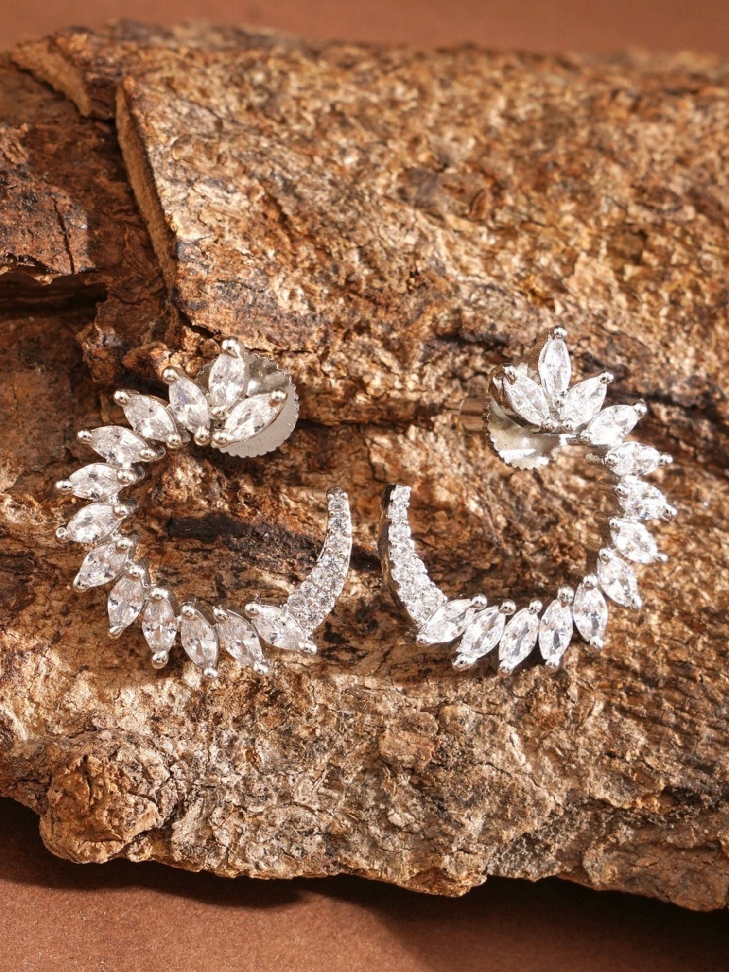 Sparkling Silver Plated American Diamond Stud Earring pair with marquise stones on textured earthy background