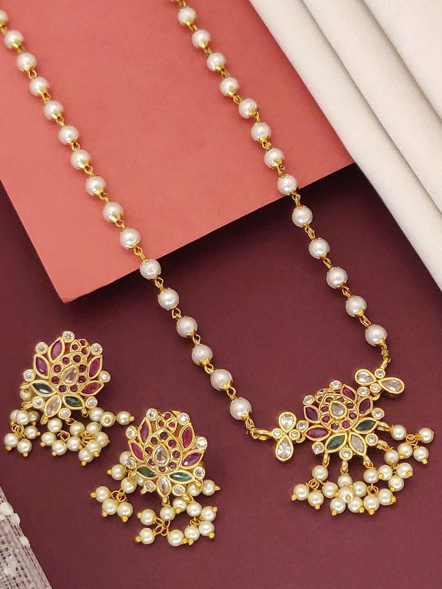 Traditional gold plated necklace with intricate floral design and matching earrings adorned with pearls