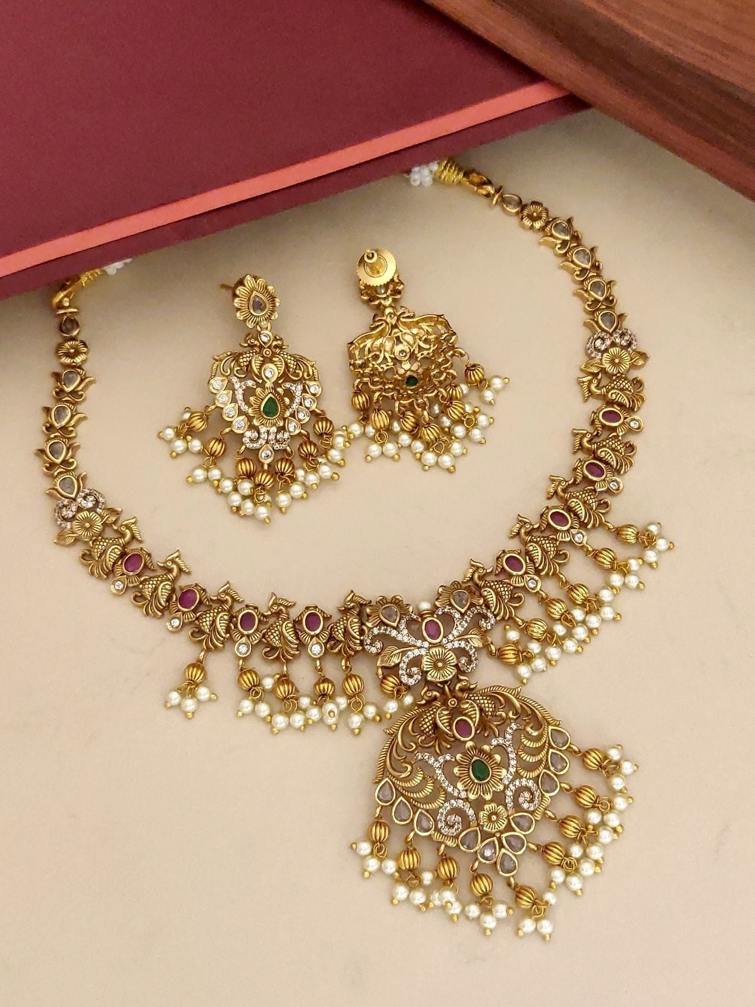 Traditional gold plated necklace set with intricate design and colorful gemstone accents
