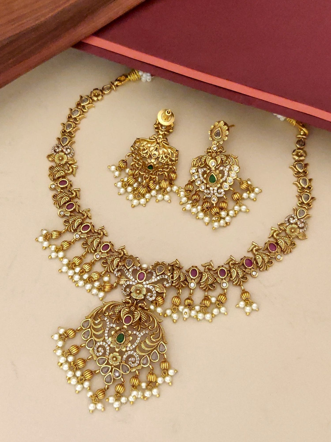 Traditional gold plated necklace set with intricate design and colorful gemstone accents