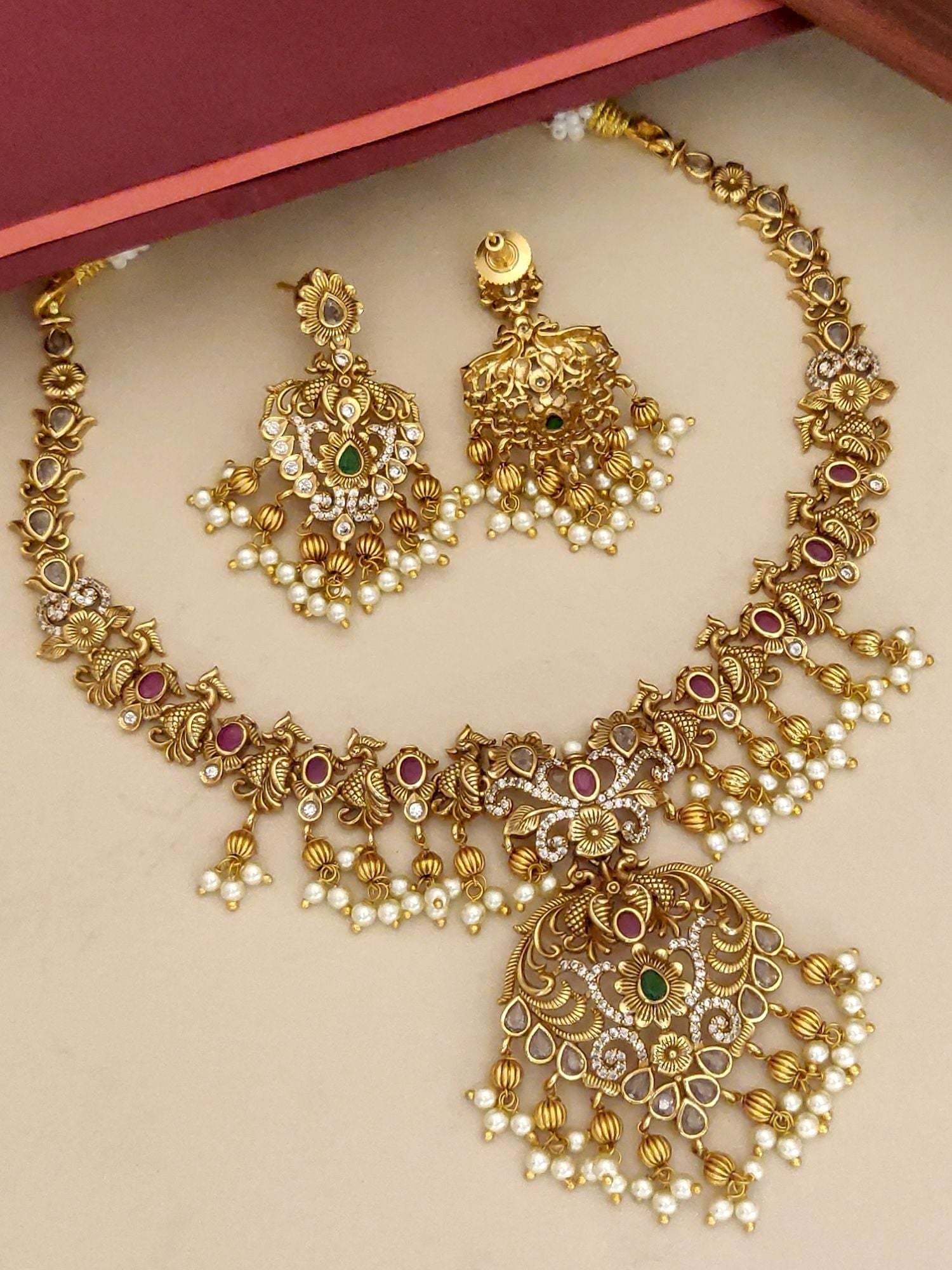 Traditional gold plated necklace set with intricate designs and pearl embellishments