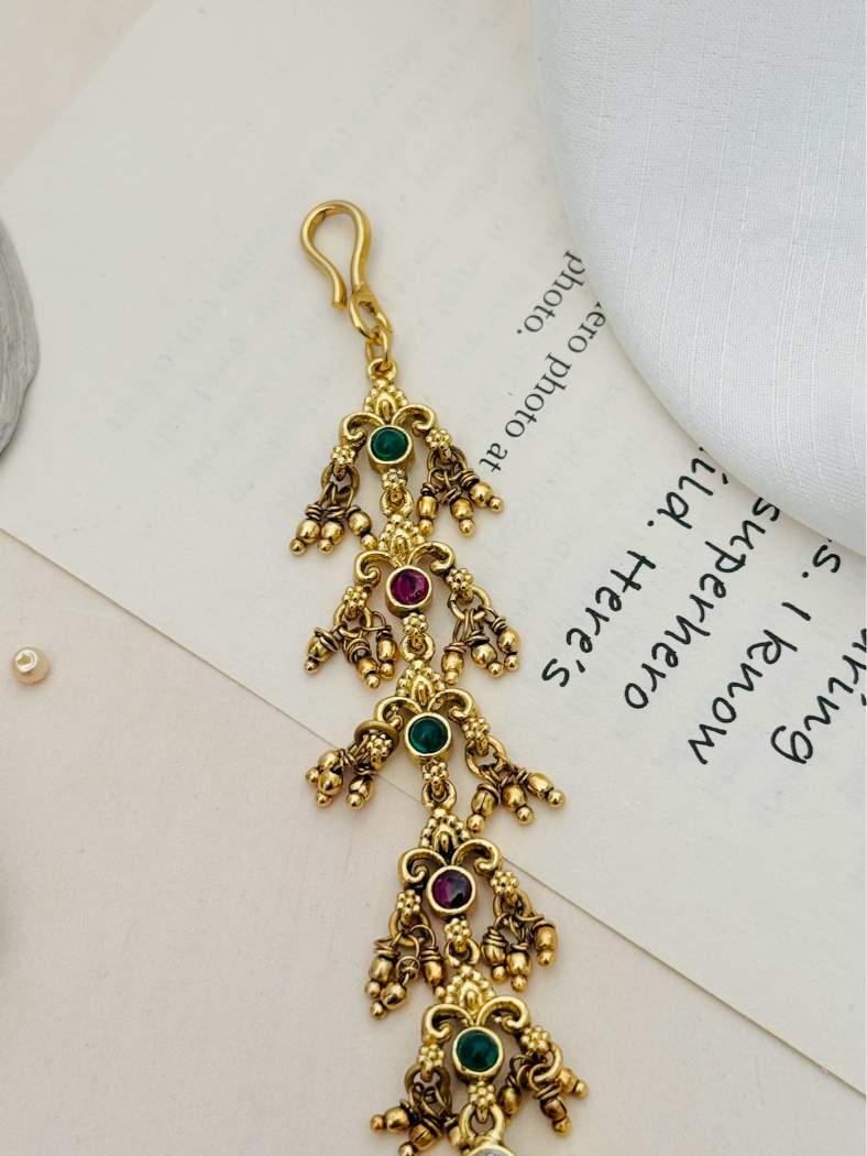Traditional Matt Gold Plated Temple Maangtikka with green and purple stones and intricate detailing