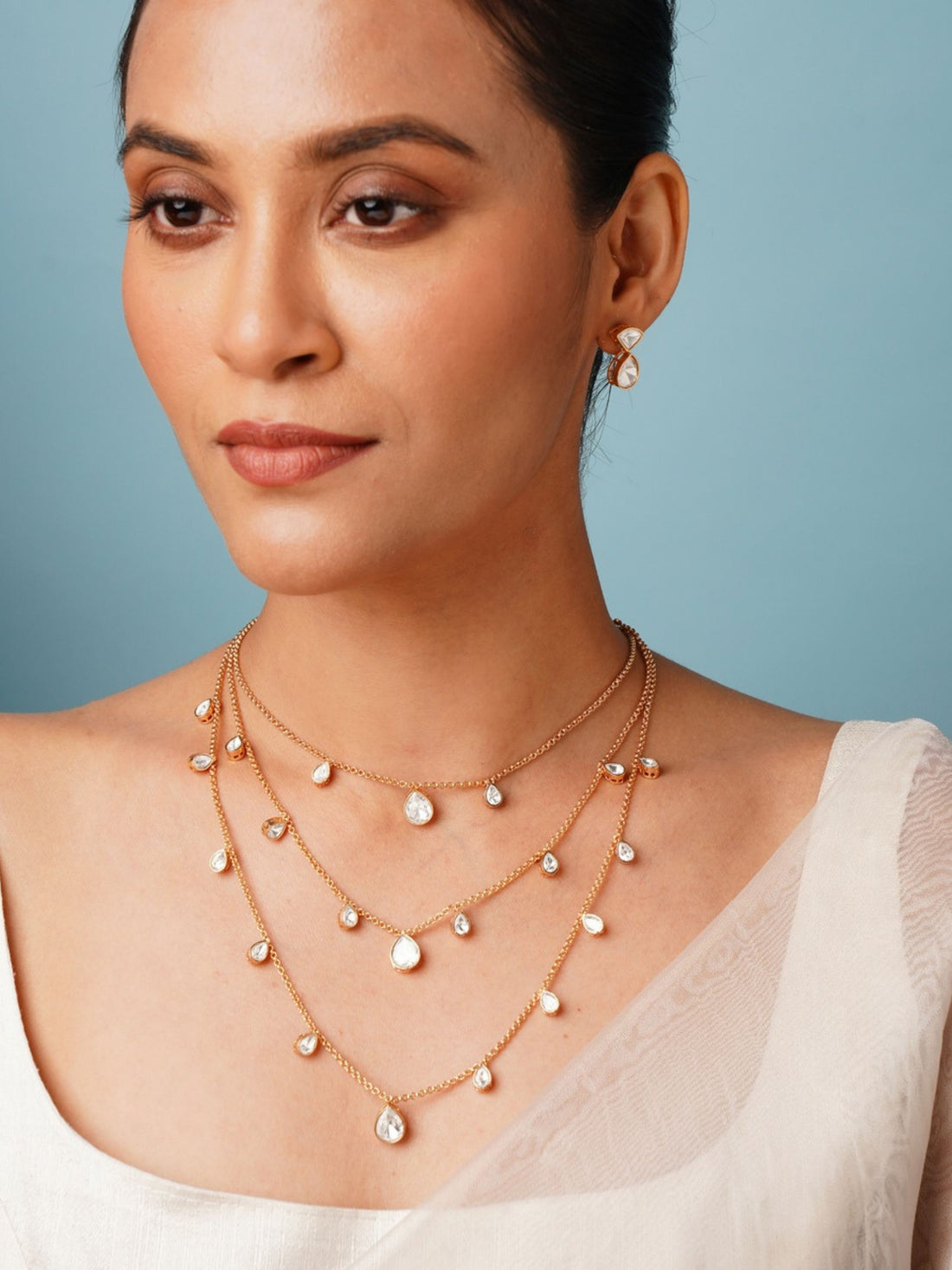 Layered Gold Plated Polki Pendant Chain worn by woman with white top and blue background