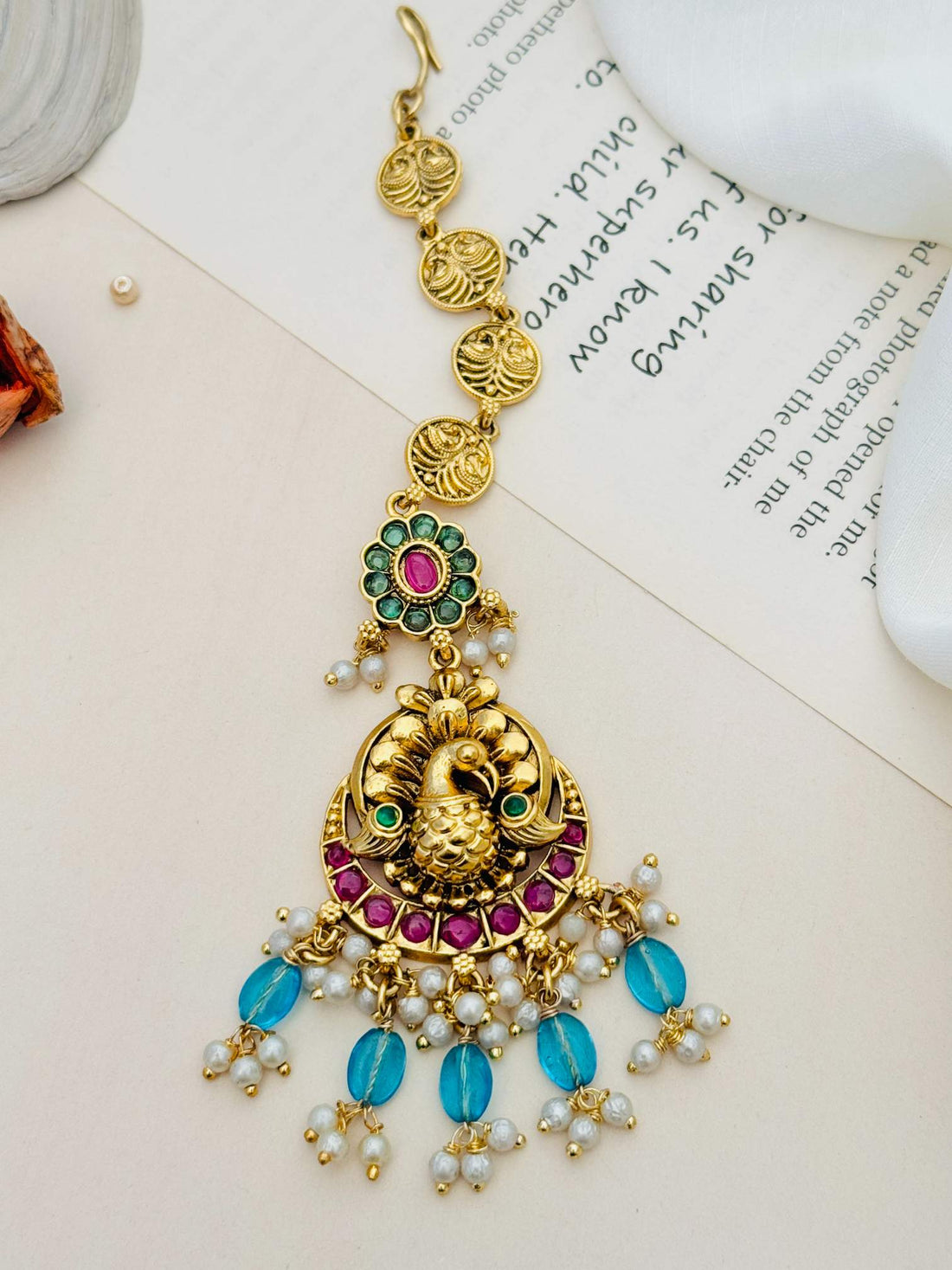 Multistone Sky Blue Matt Gold Plated Peacock Style Maangtikka worn on forehead by woman