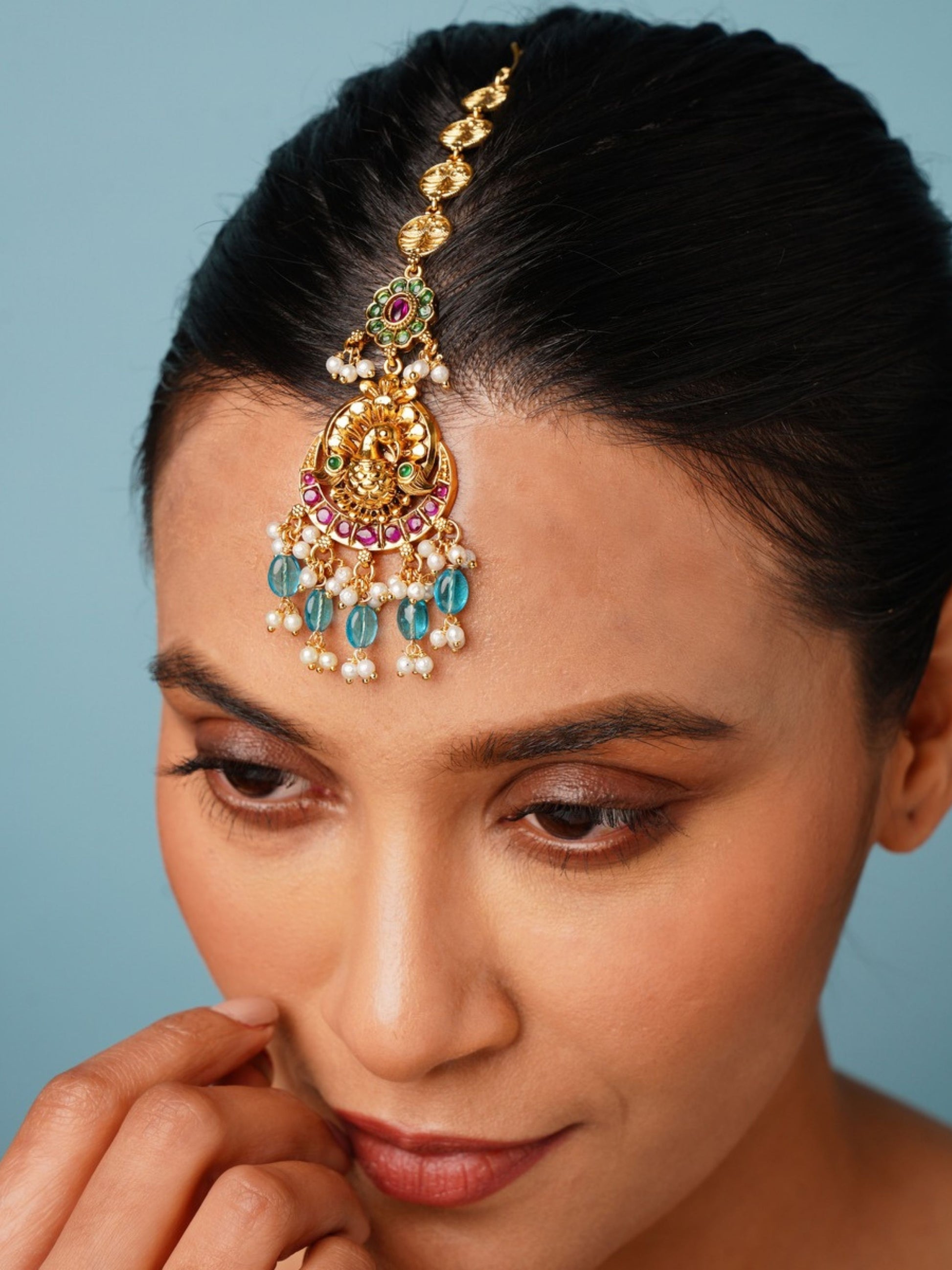 Multistone Sky Blue Matt Gold Plated Peacock Style Maangtikka worn on forehead by woman