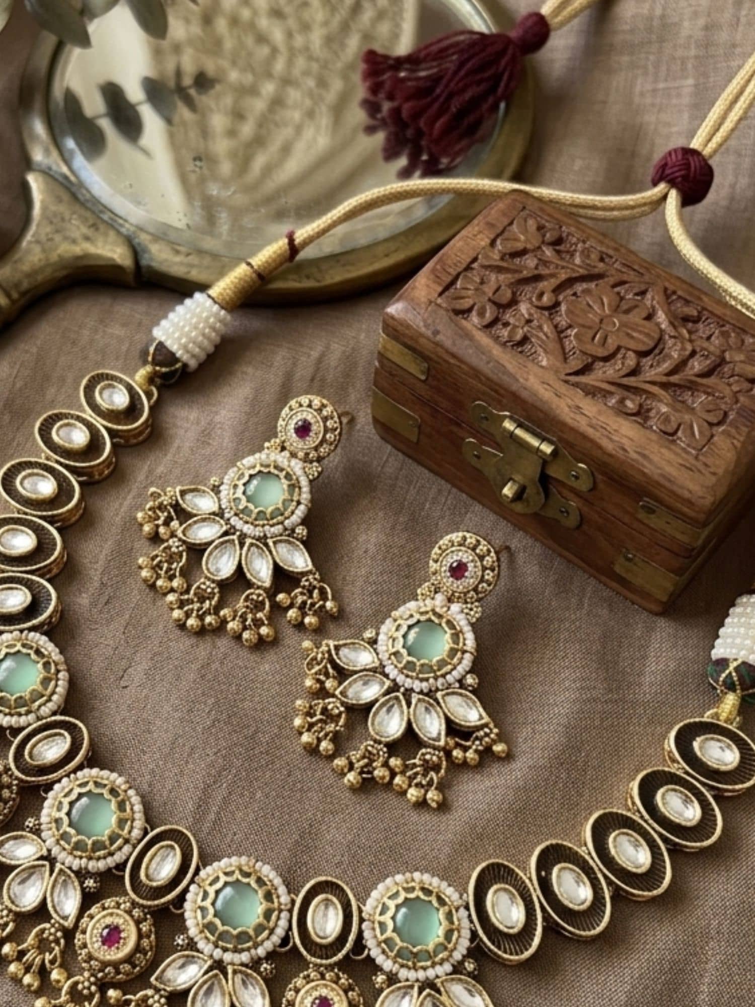 Elegant necklace for gold with intricate design and matching earrings, displayed on silk fabric
