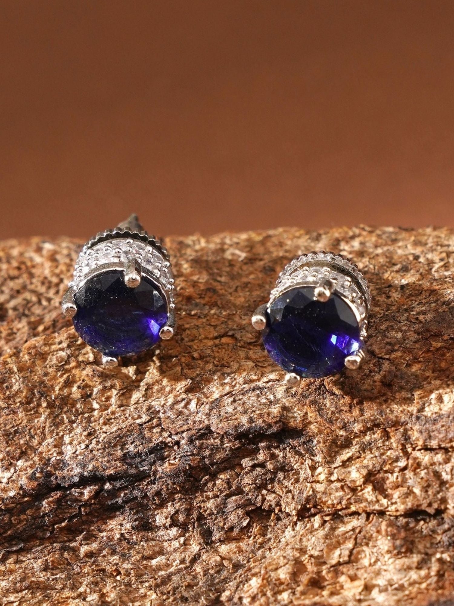 Precious Silver Plated American Diamond Stud Earring with deep blue stones on textured surface