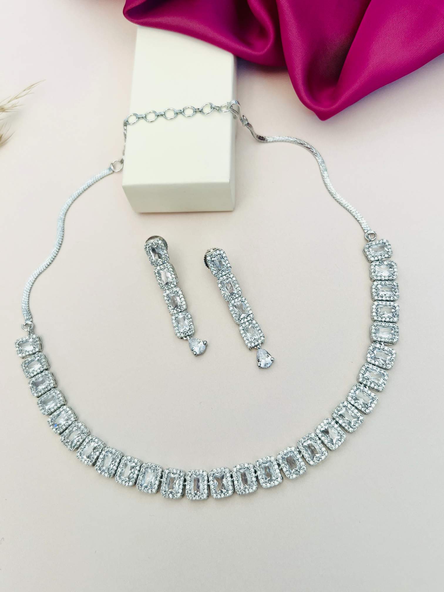 Silver American Diamond Necklace Set with matching earrings by Abdesignsjewellery displayed on a white surface
