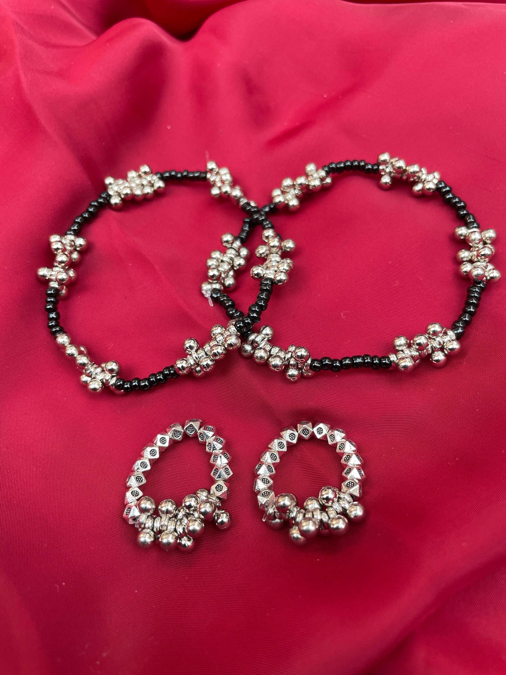 gungru anklet toe ring combo black beaded anklets with silver floral clusters and matching silver toe rings on red fabric