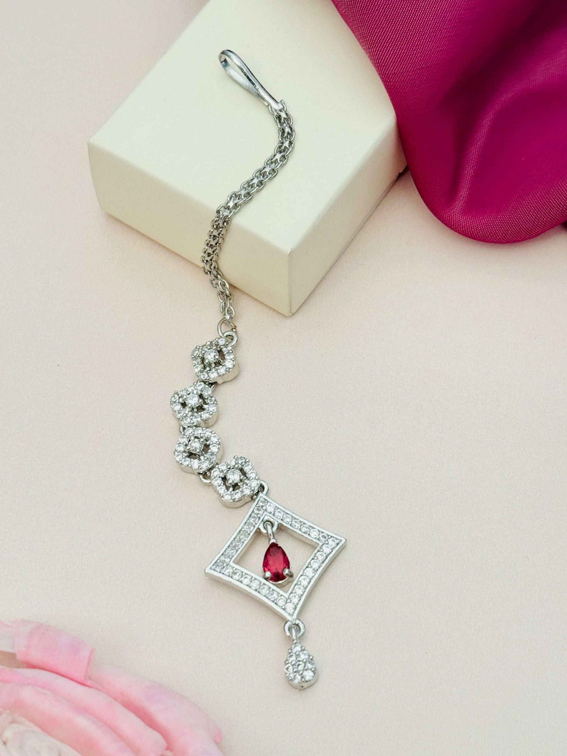 Silver Plated American Diamond Maangtikka with a red stone and intricate floral design by Abdesignsjewellery