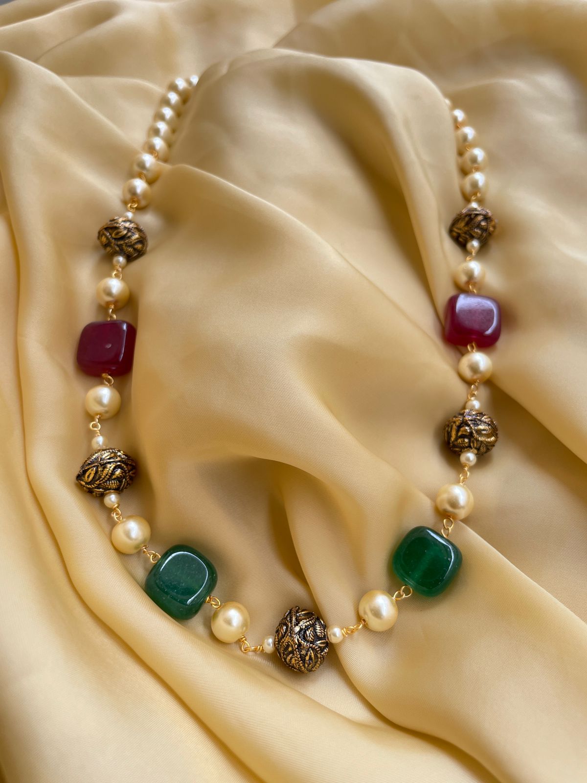 Abdesignsjewellery Mala Necklace with Colorful Beads and Golden Accents on Soft Fabric Background