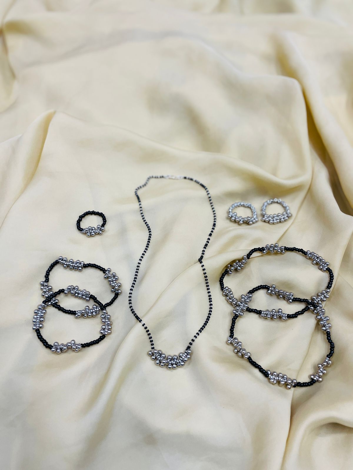 Abdesignsjewellery gungru anklet toe ring combo black beaded anklets toe rings and matching chain on cream fabric